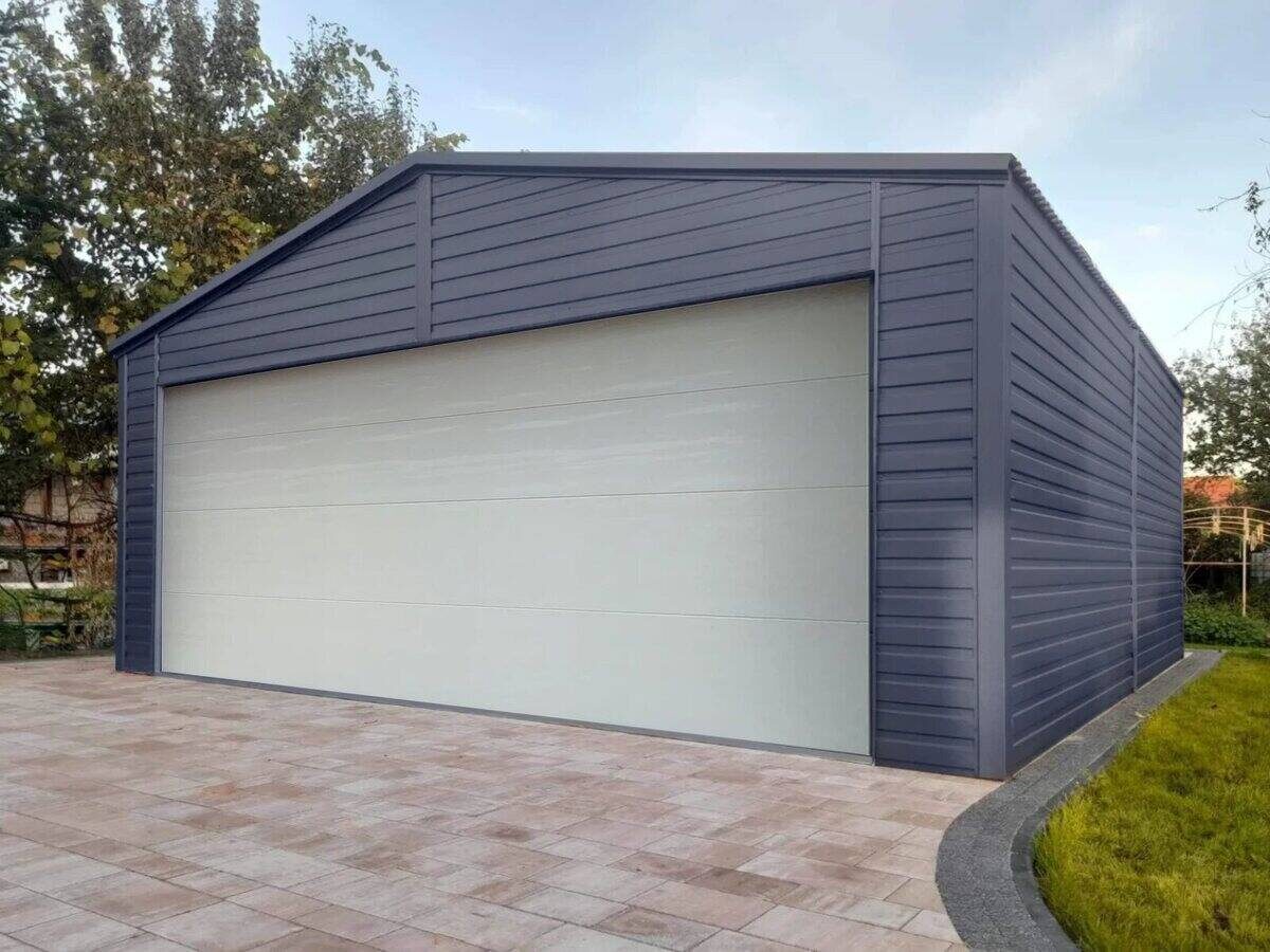 Anthracite-clad garage with a pale grey insulated sectional door on block paving