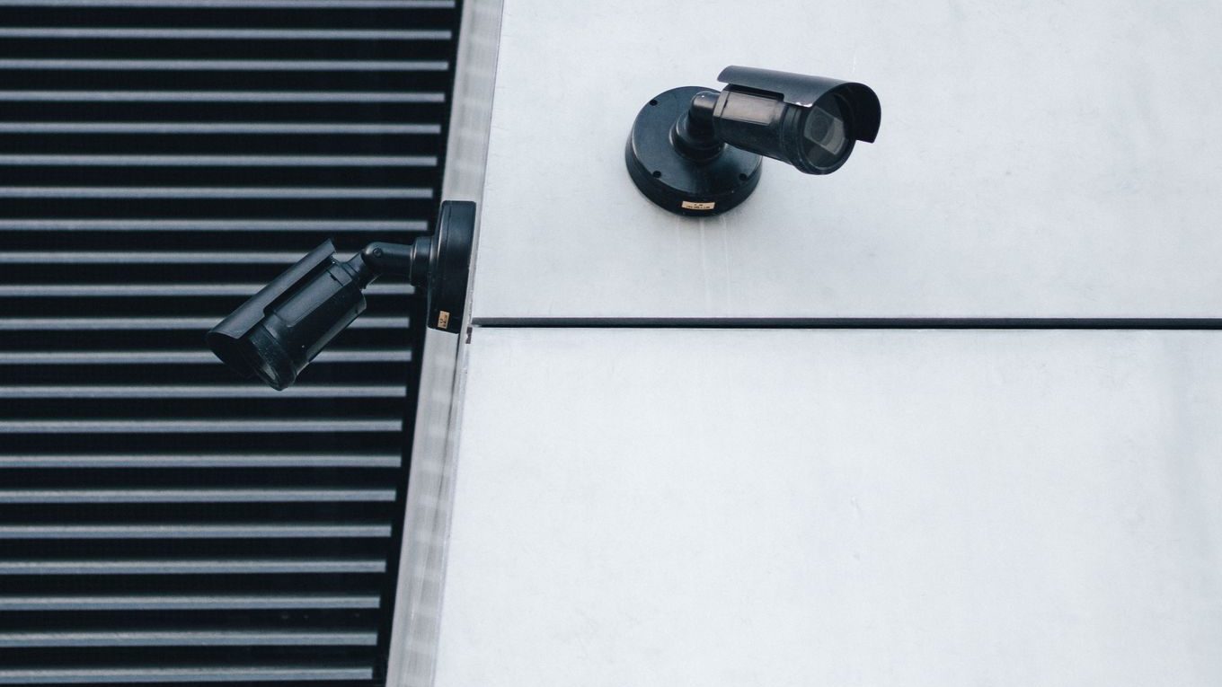 Black security cameras mounted high on a modern building