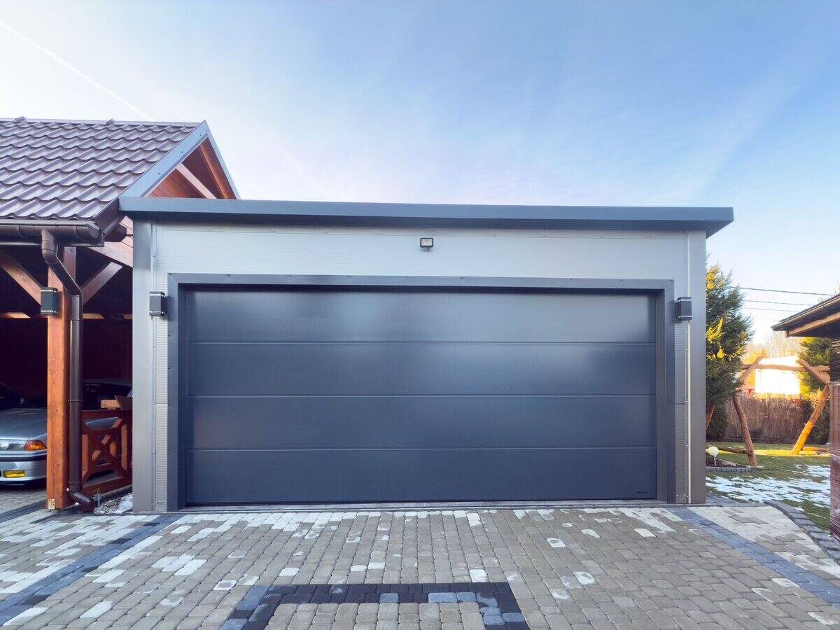 Anthracite insulated PIR garage with side window, front three-quarter view in residential garden setting