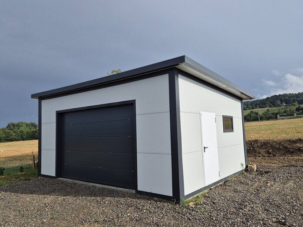 White insulated PIR garage with anthracite sectional door, front view on paved area