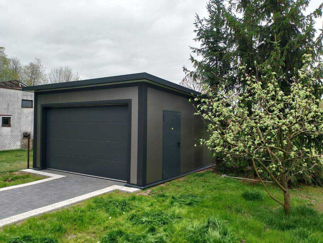Anthracite insulated PIR garage, front three-quarter view from left in garden with spring blossom tree