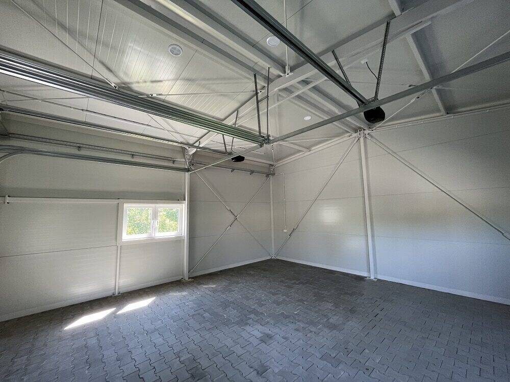 Insulated garage interior with white PIR panels and a side window, paved floor