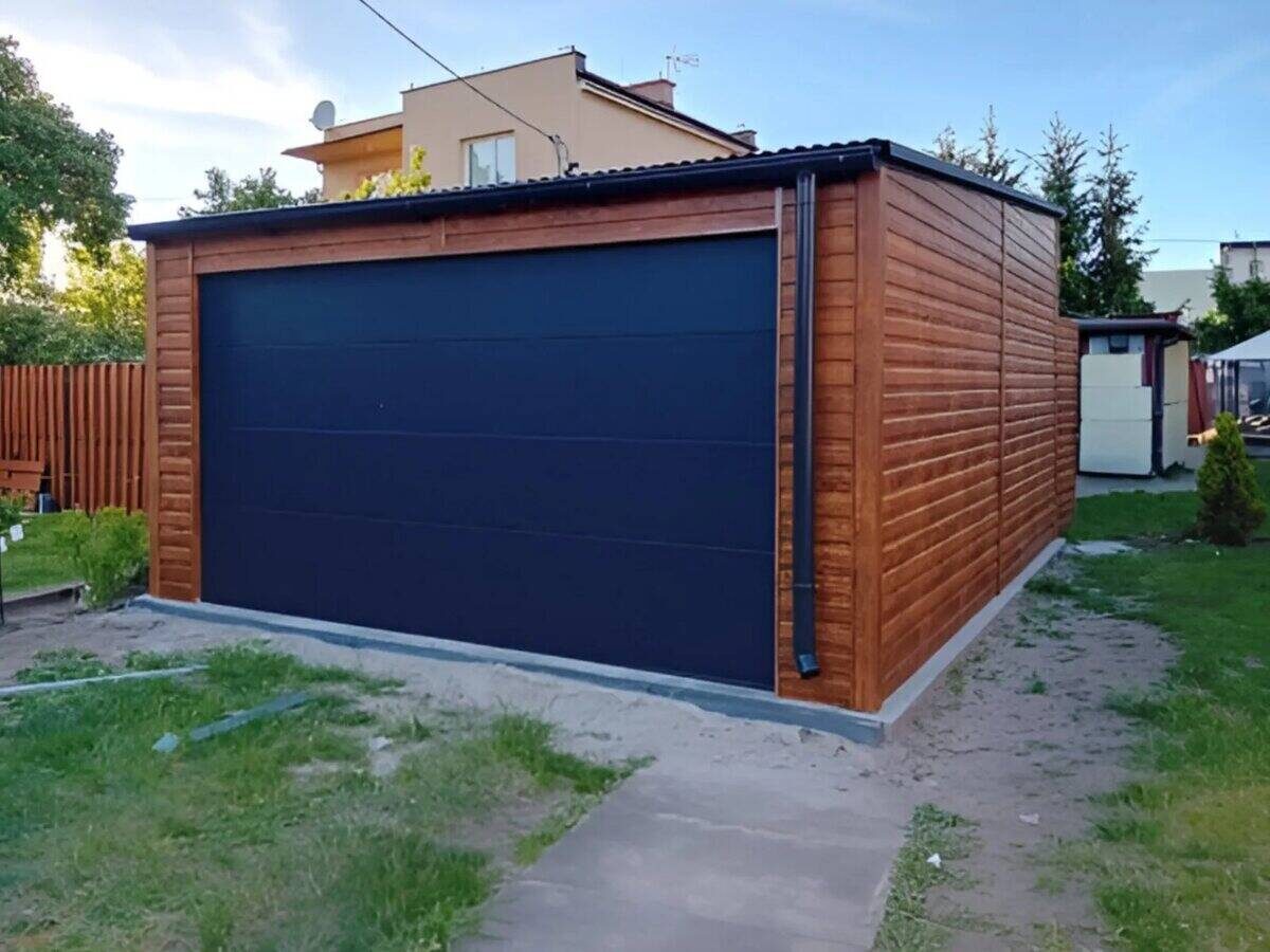 Steel garage with dark walnut wood-effect sectional door, front view on paving