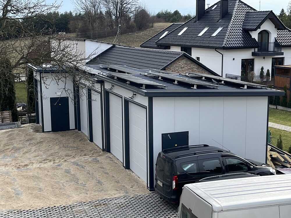 Four-bay insulated garage with a solar roof beside a brick house