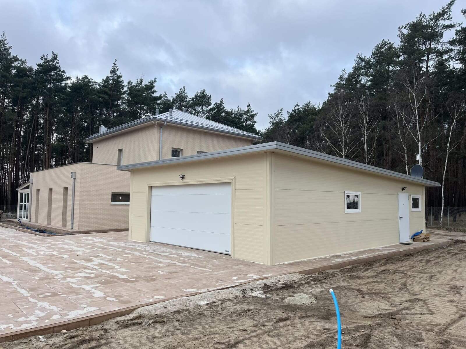Beige insulated garage alongside the main house, wide context view