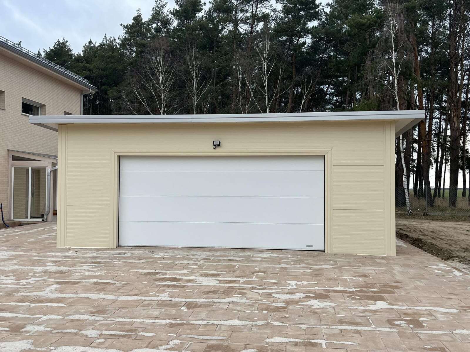 Beige insulated garage, straight-on hero view with the house partly visible