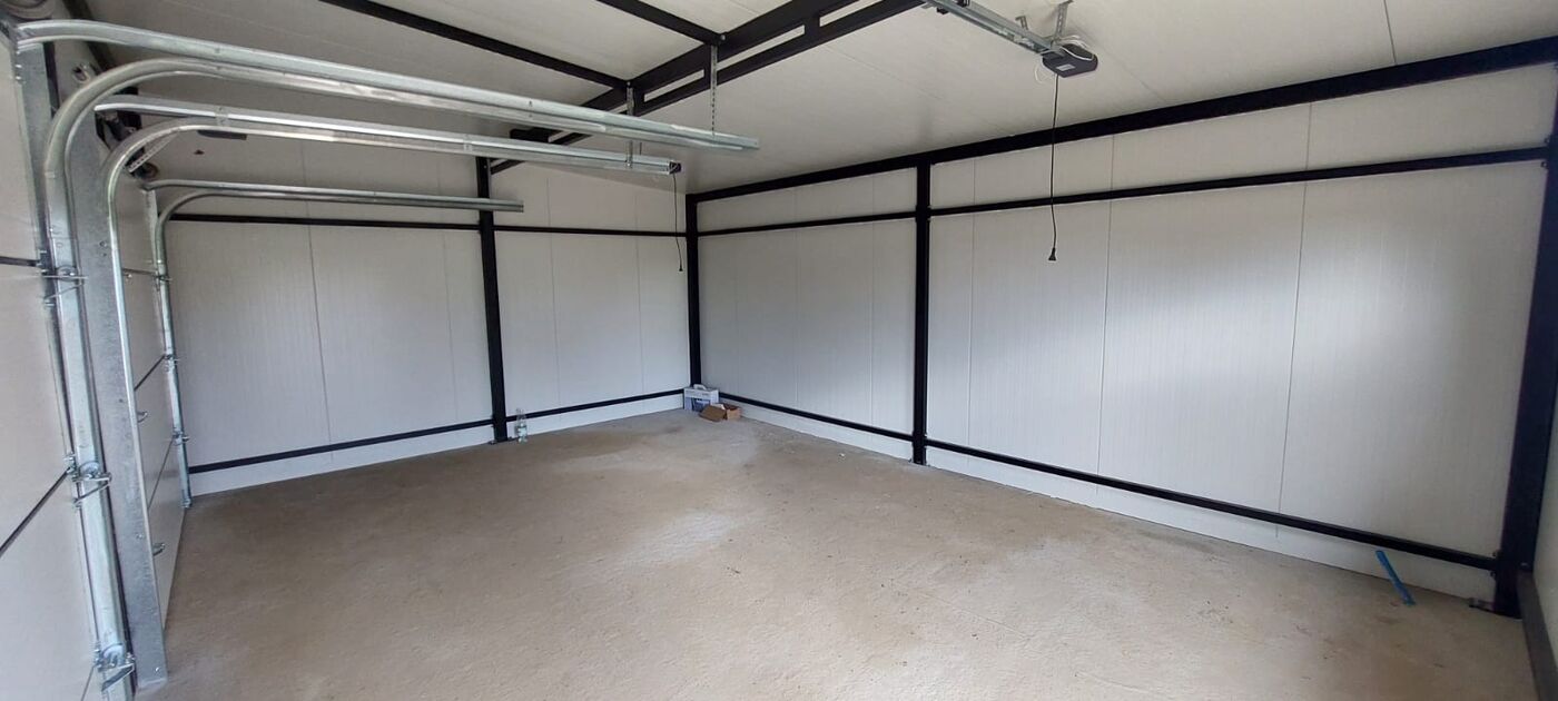 Insulated double garage interior with white PIR wall panels and a rear window