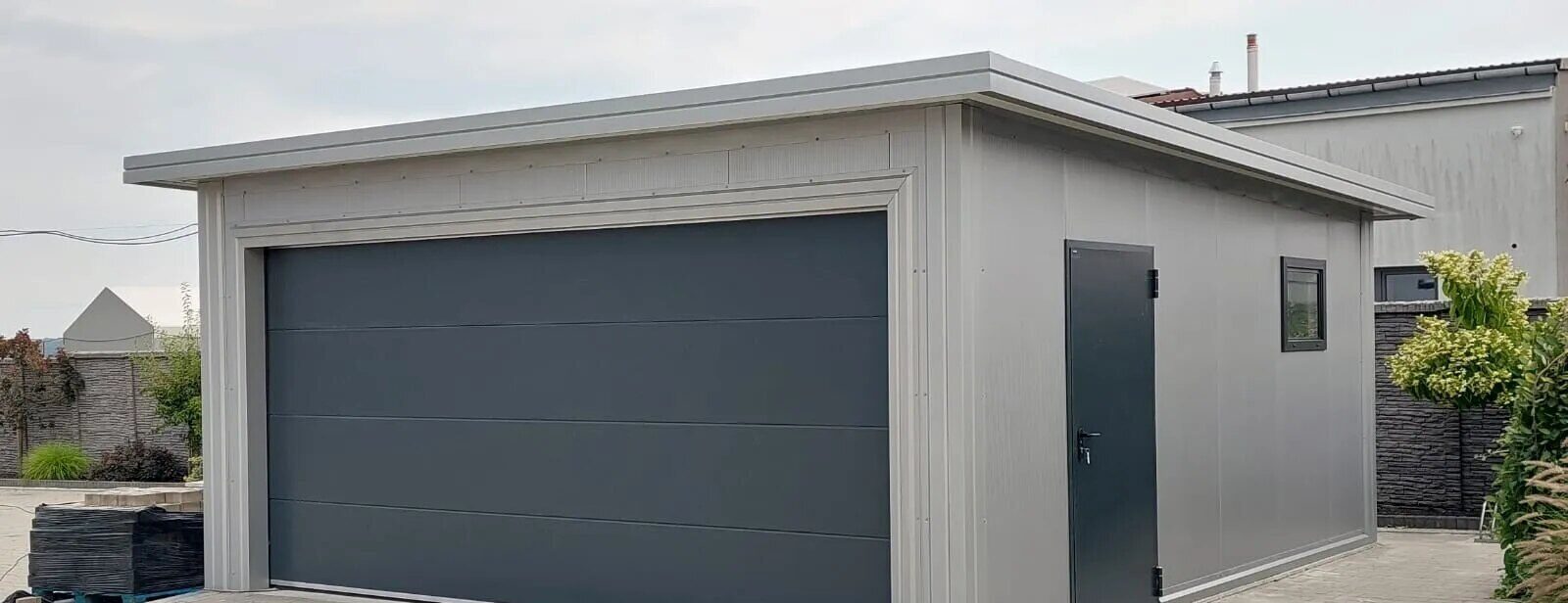 Insulated garage with anthracite sectional door and grey insulated cladding