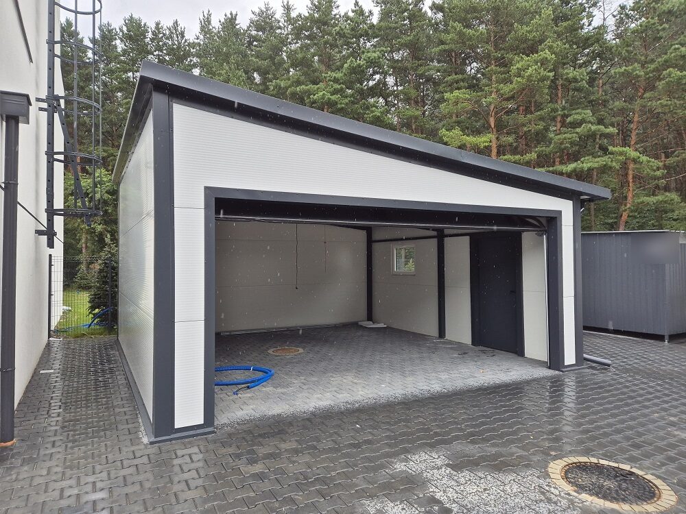 Insulated garage in white panels with its wide door open onto a paved floor