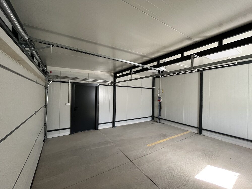 Inside an insulated garage: panel walls, a side entrance door and a concrete floor
