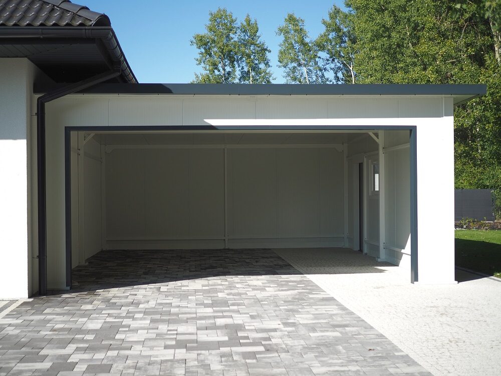 Insulated garage structure attached to a house in a landscaped garden setting