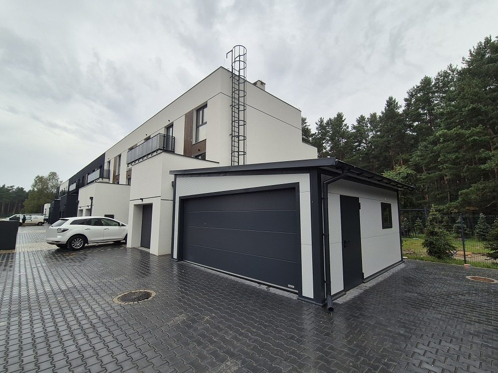 White insulated garage attached to a modern house, sectional and personnel doors visible