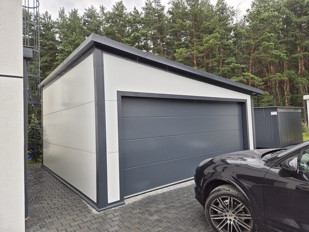 Insulated garage in white panels with one wide anthracite sectional door and a car parked in front
