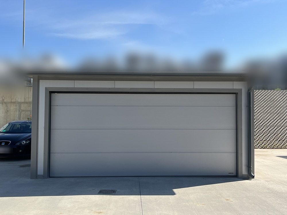 Light grey insulated garage, straight-on front elevation with a wide sectional door