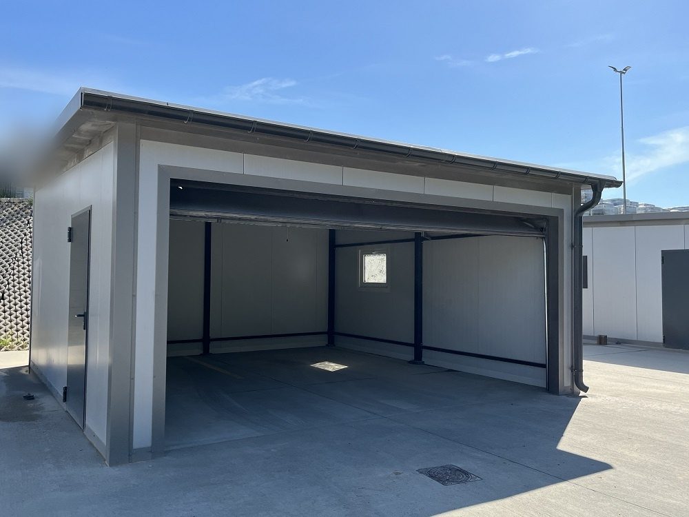 Insulated garage with the door open, seen from the front-left with the side personnel door in view