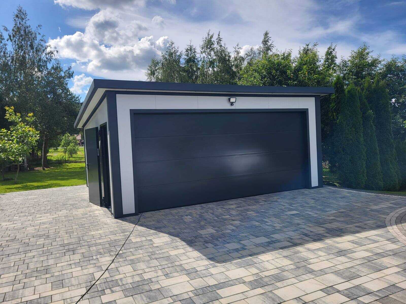Insulated garage with anthracite double sectional doors on a block-paved driveway, front-left view