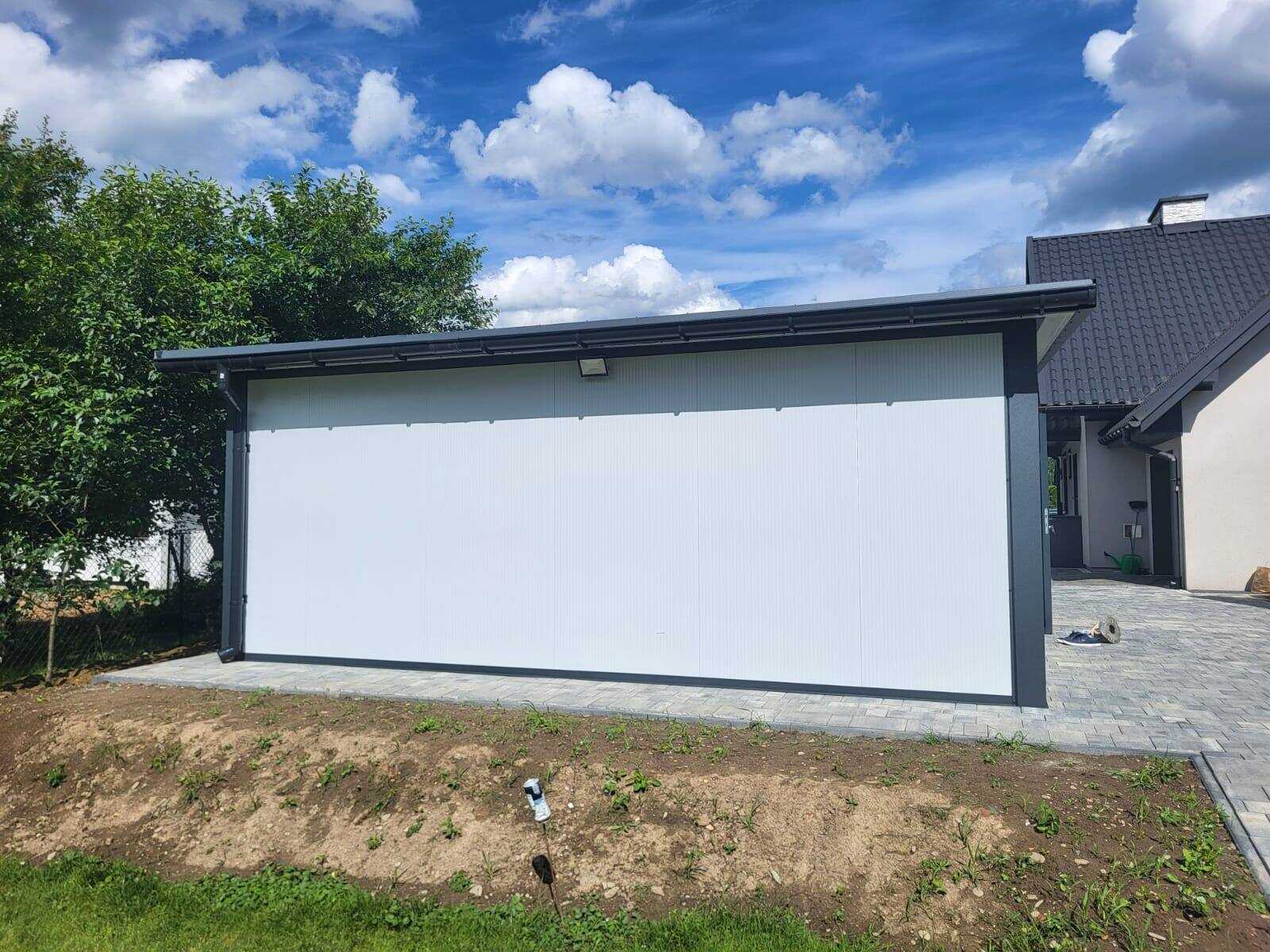 Rear three-quarter view of a white insulated garage beside a house