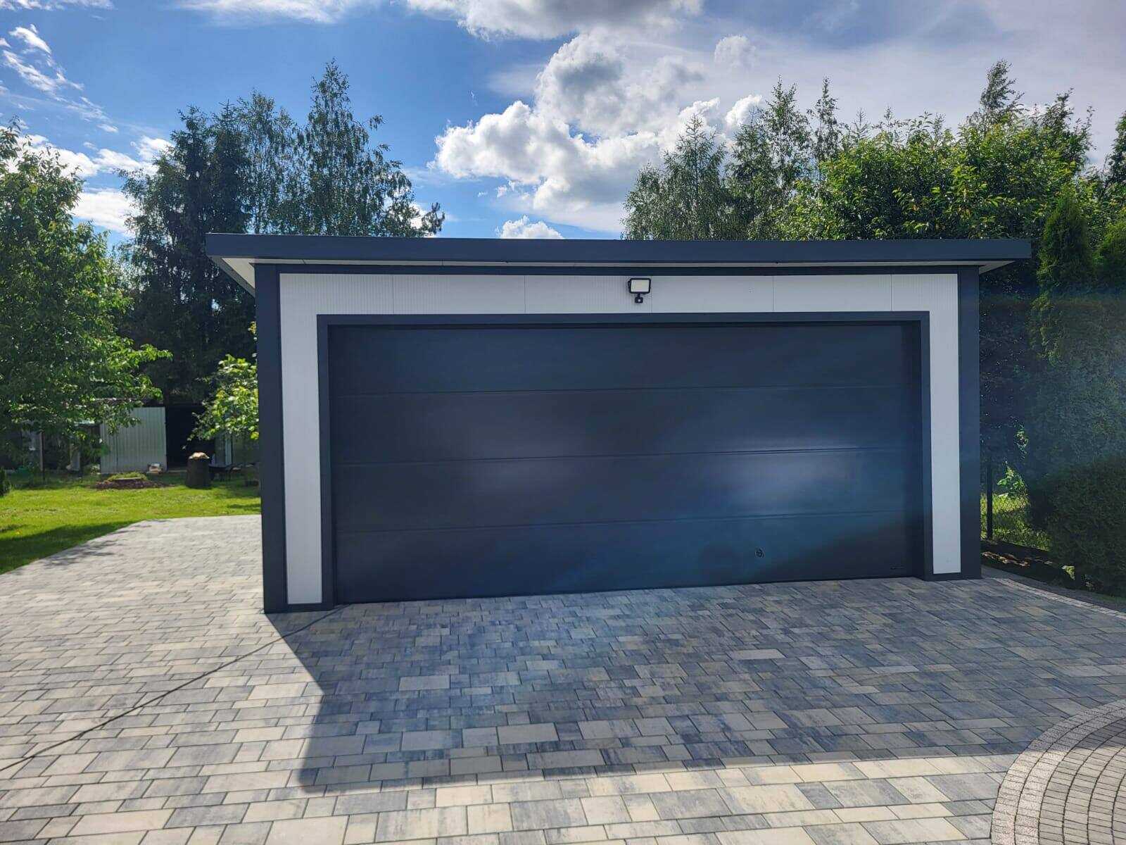 Insulated garage, front three-quarter view with anthracite double sectional doors on block paving