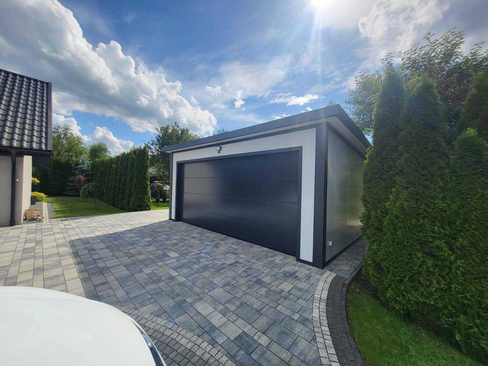 Insulated garage at golden hour with an anthracite door beside a clipped hedge