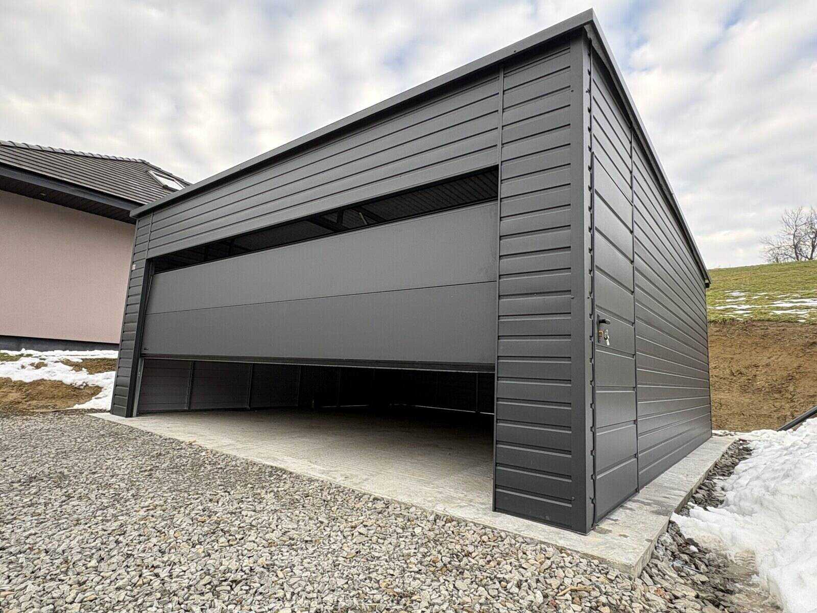 Anthracite steel garage, three-quarter view in a rural setting