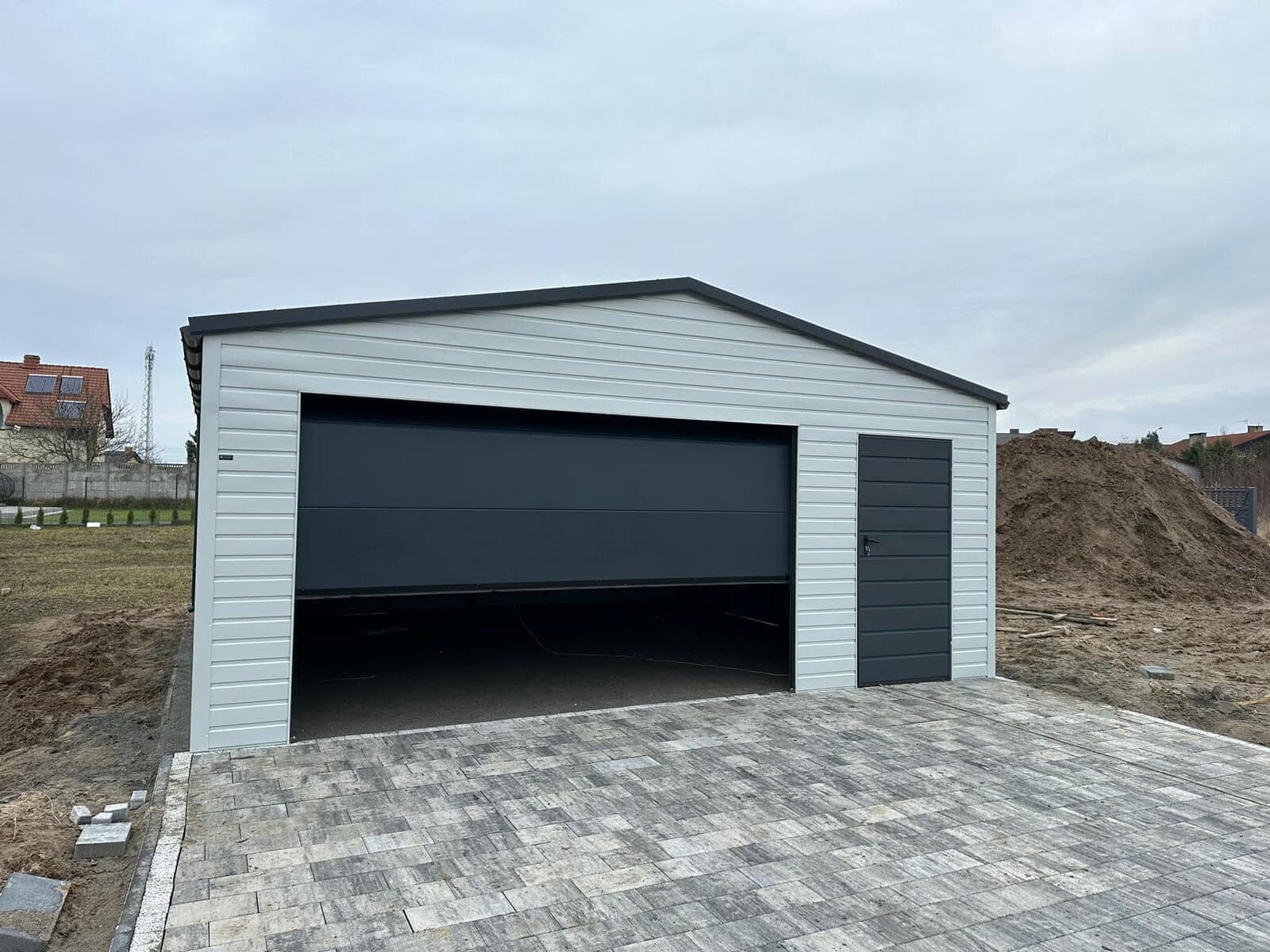 Interior of a light grey steel garage looking out through the open sectional door