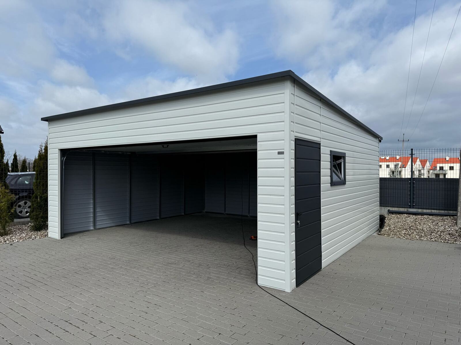 White-clad steel garage with its wide door open, showing the anthracite interior walls