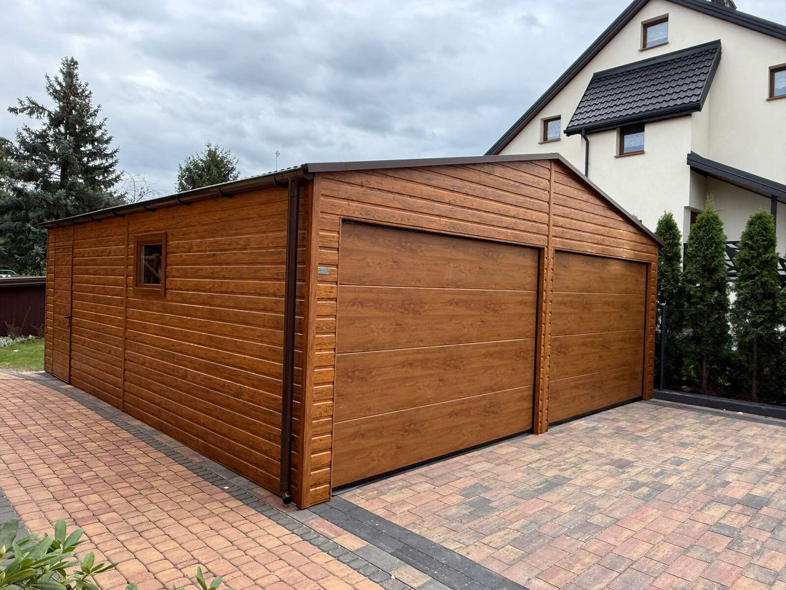 Wood-effect steel garage with twin sectional doors, a separate personnel door and window, three-quarter view