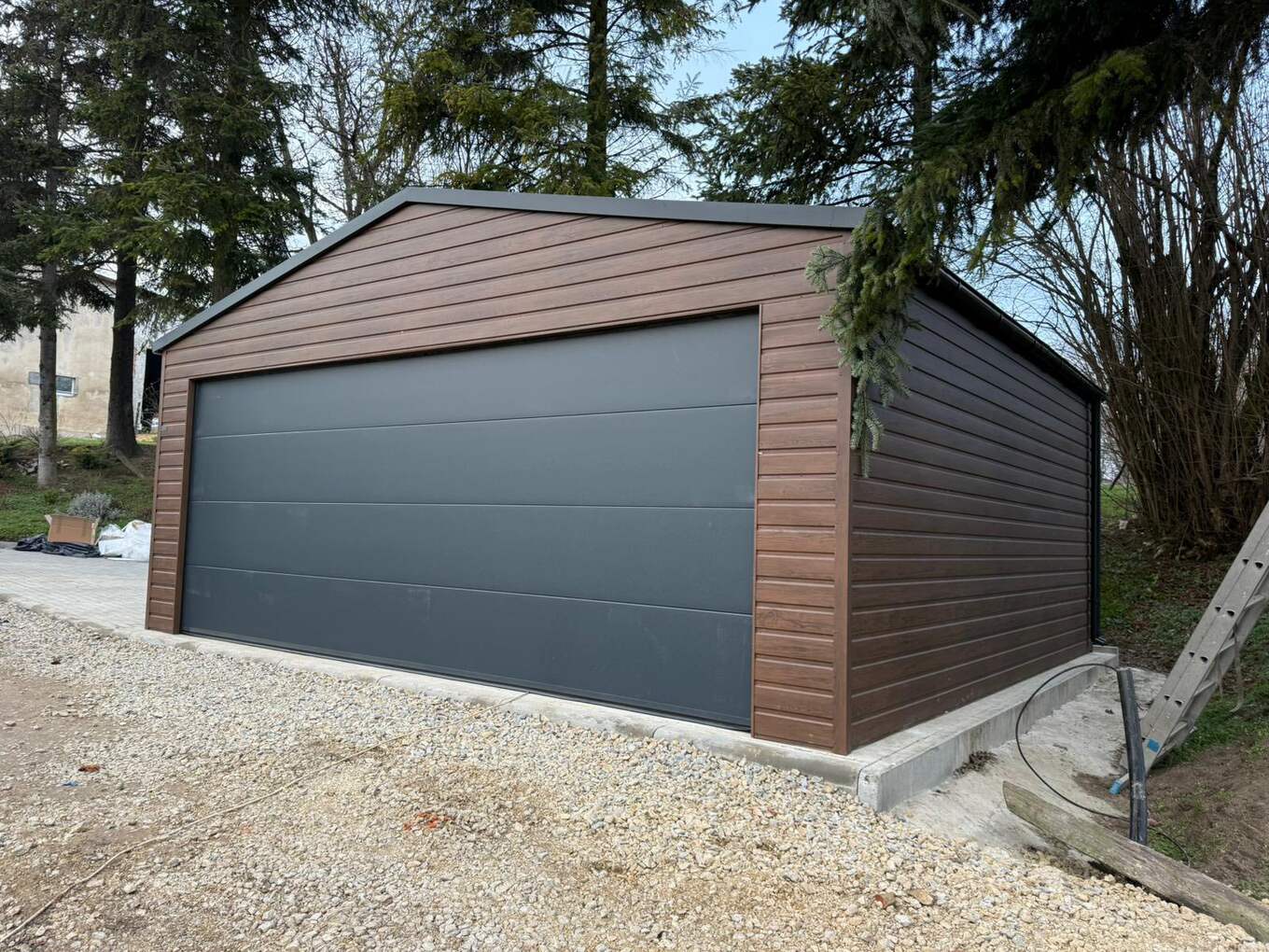 Wood-effect steel garage, gable-end three-quarter view on a gravel base