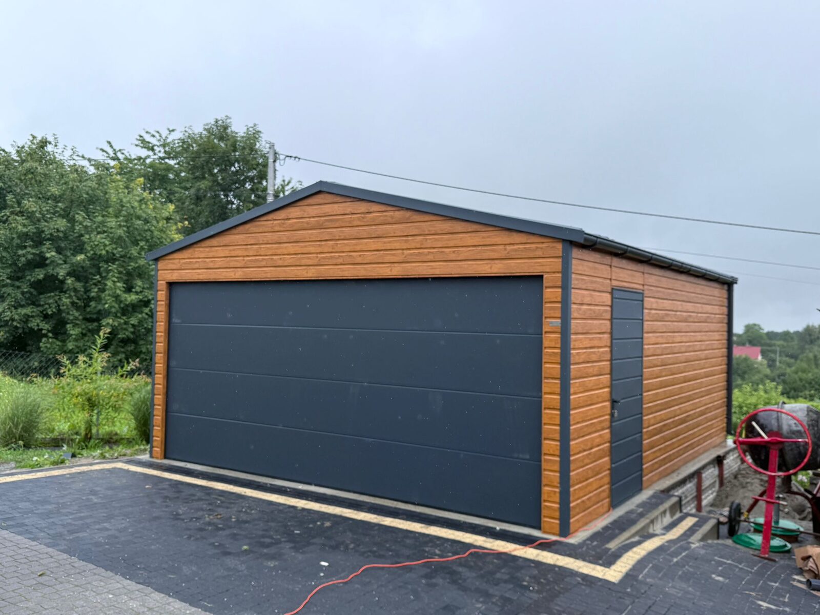 Wood-effect steel garage with a dark sectional door, front three-quarter view, door closed