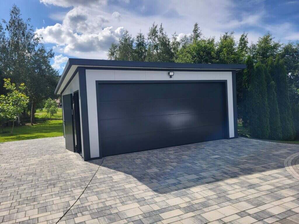 Insulated garage with anthracite double sectional doors on a block-paved driveway