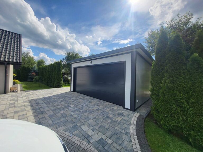 Insulated garage at golden hour with an anthracite door beside a clipped hedge
